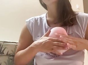 Woman plays with small pink balloon (the balloon doesn't burst)