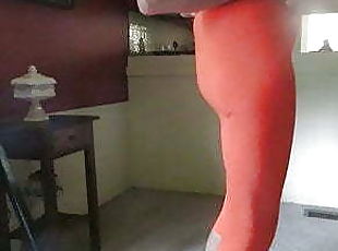 Male slut in skin-tight, bright orange spandex leggings.